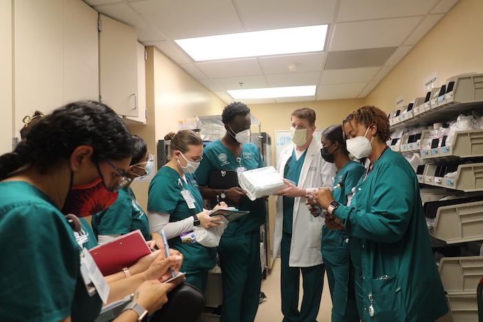 A nursing teacher with a group a students, teaching about healthcare supplies in a supply room.